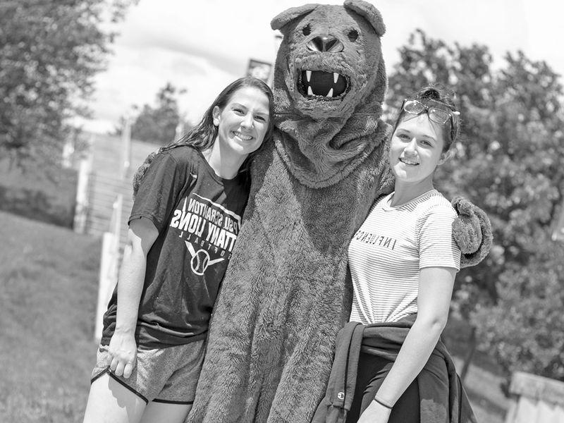 nittany lion  mascot has arms around two students