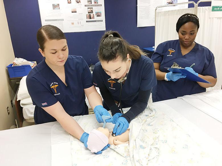 three nursing students practice on infant simulator