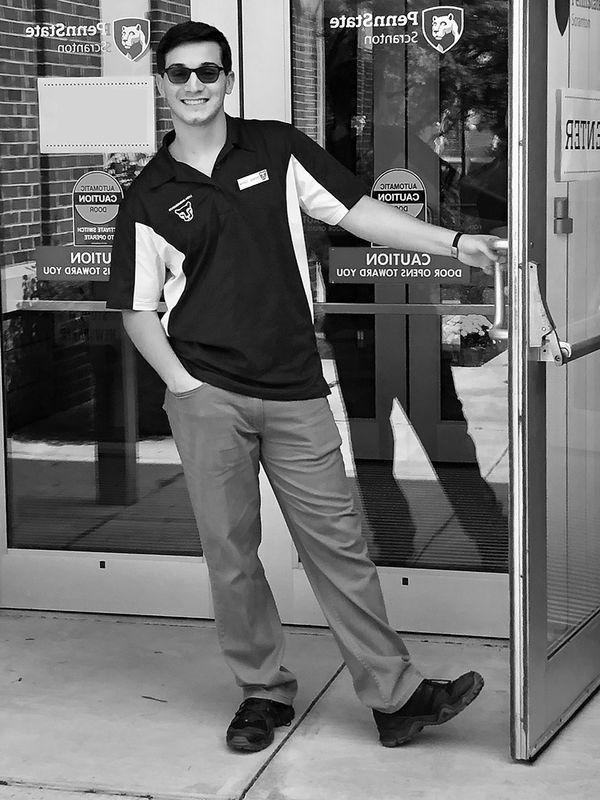 student smiling holding the door open