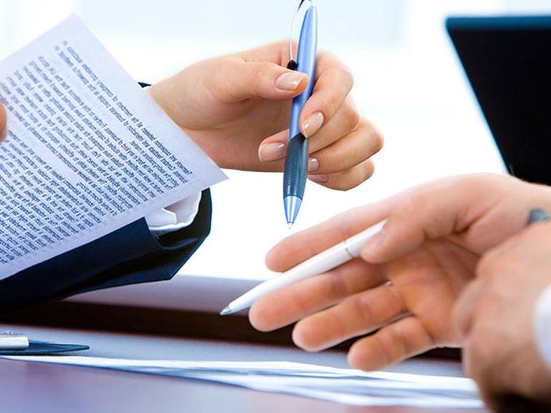 the hands of two people pictured reviewing paper work
